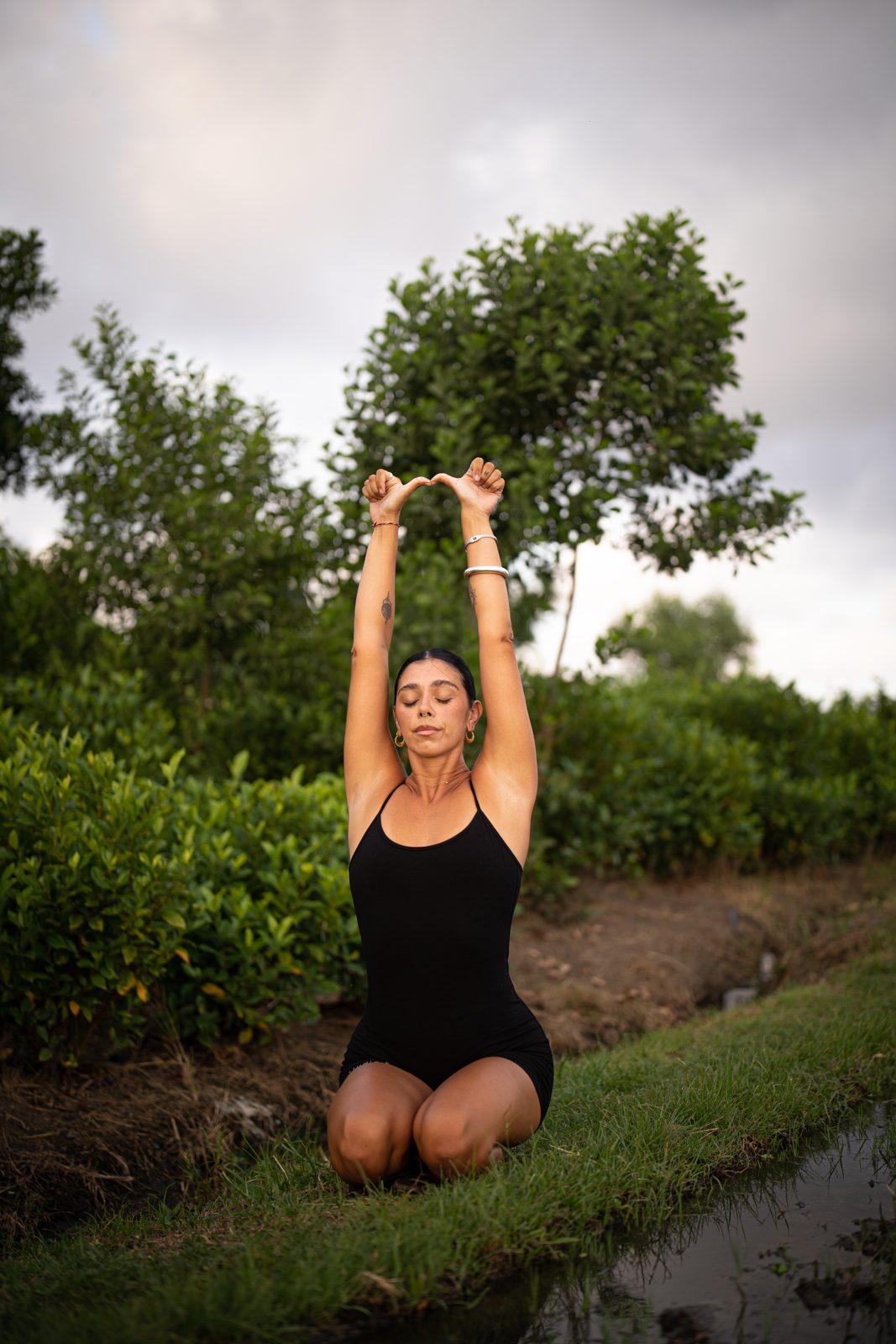 Irene del Valle kneeling and reaching upward in a green field
